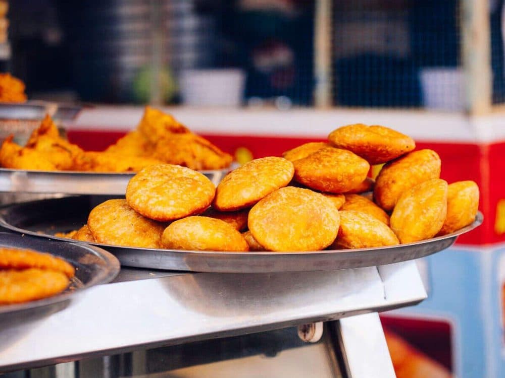 A steel plate piled high with freshly fried kachoris at a Jaipur street stall